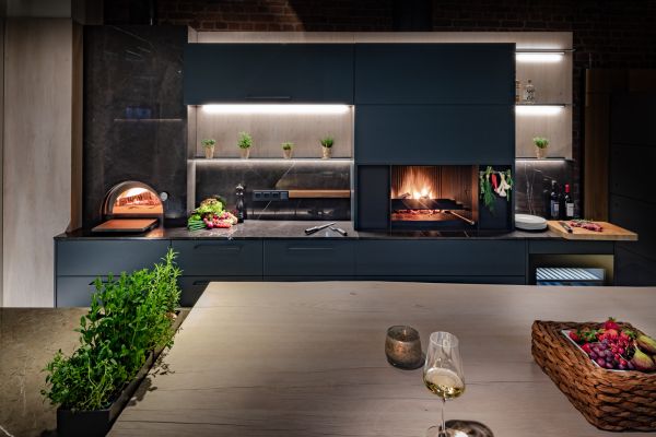 Moderne Wohnküche mit Holzofen, Feuerstelle, Kräutern und gedecktem Tisch in stilvoller, gemütlicher Atmosphäre.