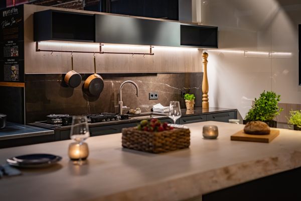 Moderne Küche mit Holztisch, Brot, Kräutern und stimmungsvollem Licht für eine gemütliche Kochatmosphäre.