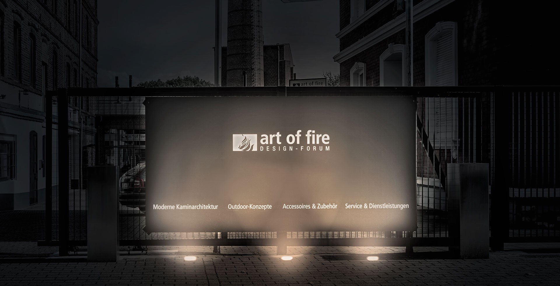 Beleuchtetes Eingangsschild des „art of fire DESIGN-FORUM“ mit Aufschrift zu Kaminarchitektur, Outdoor, Zubehör und Service.