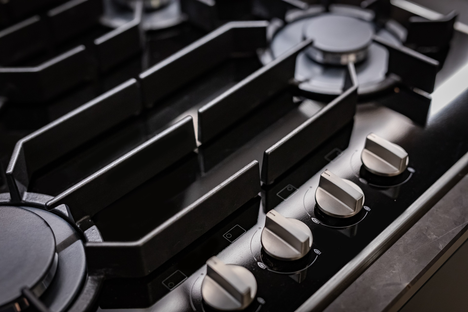 Nahaufnahme eines modernen Gaskochfelds mit mehreren Kochstellen und Drehreglern aus Edelstahl in edlem Design.