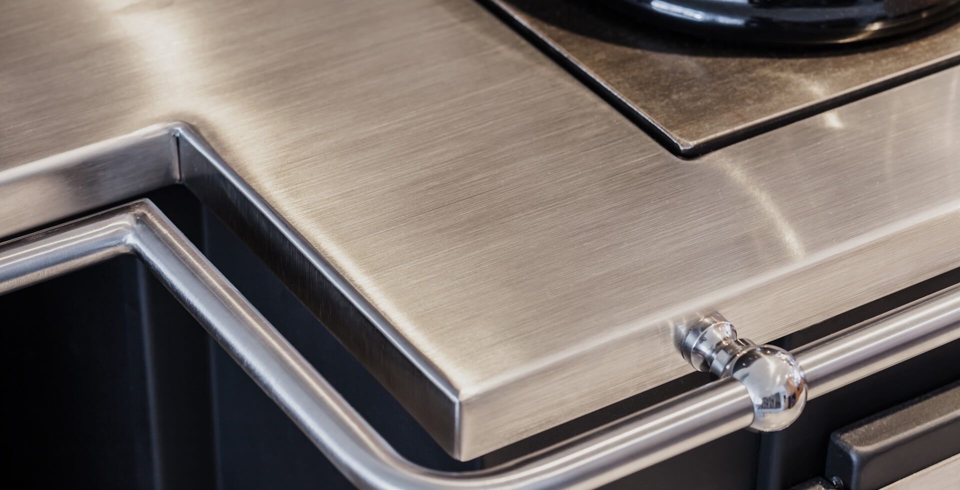 Edelstahl-Arbeitsfläche mit umlaufender Reling und glänzender Oberfläche, Detailansicht einer hochwertigen Küchenzeile.