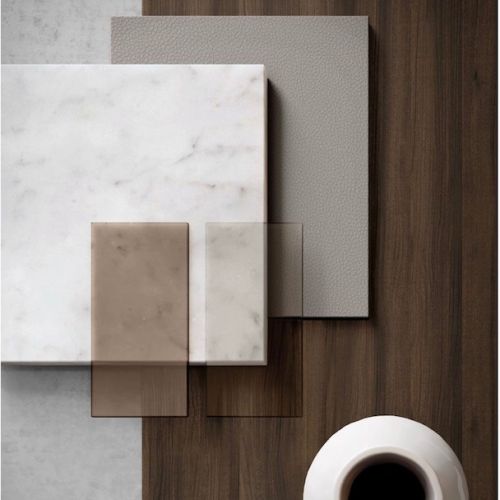 Materialmuster mit Marmor, Glas, Holz auf braunem Untergrund, daneben eine weiße Tasse mit schwarzem Kaffee.