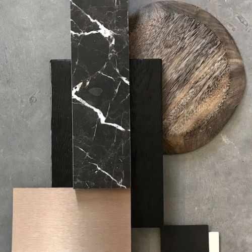 Materialcollage aus schwarzem Marmor, dunklem Holz, Bronze, Beige und Naturholz auf grauem Betonhintergrund arrangiert.